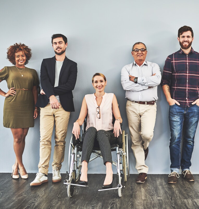 three men and one woman standing against a wall with one woman sitting in a wheelchair