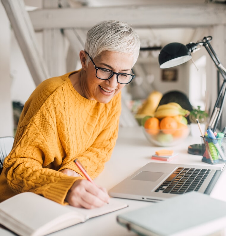 woman sitting at her desk writing in a notebook