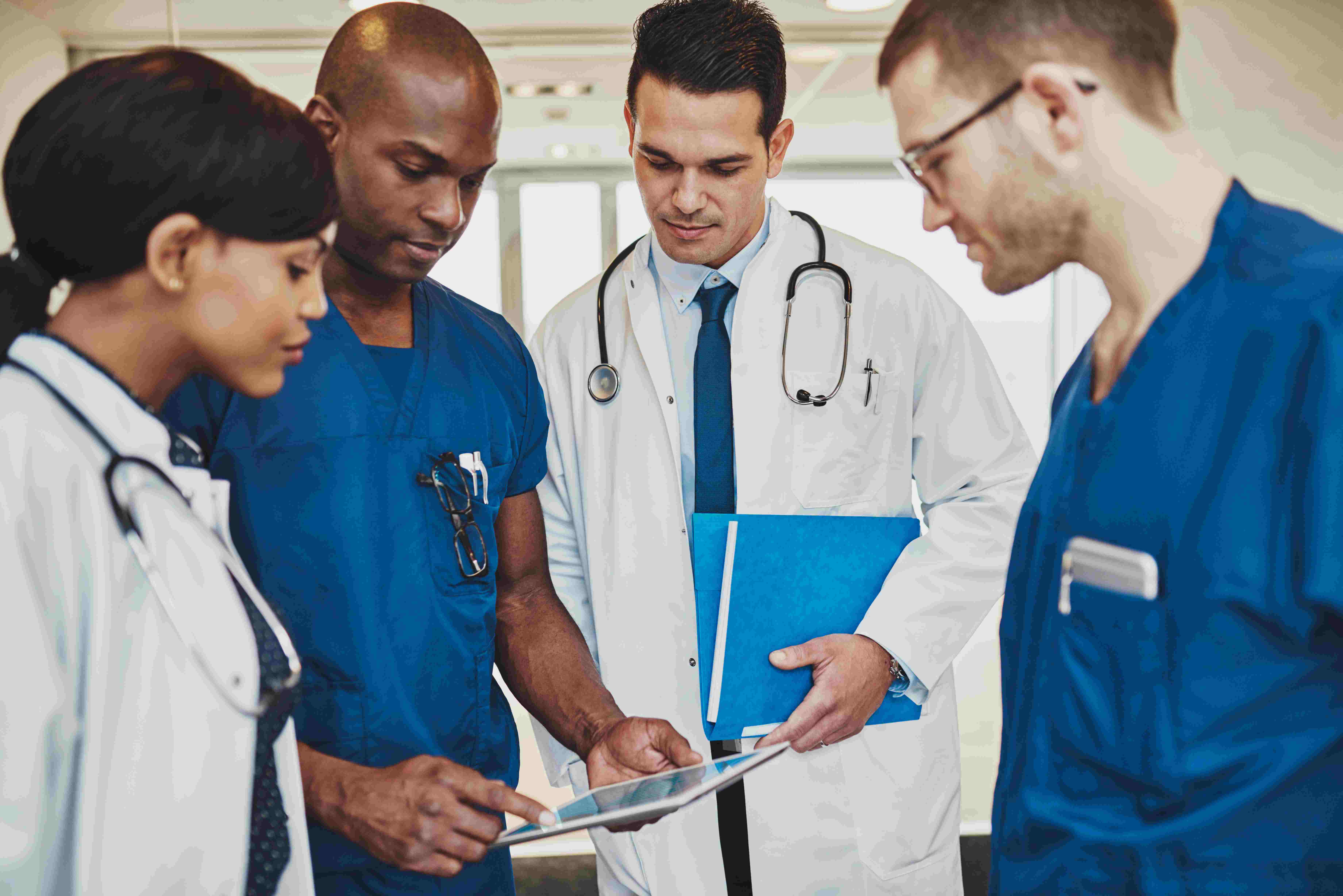 two doctors and two caregivers looking at a tablet