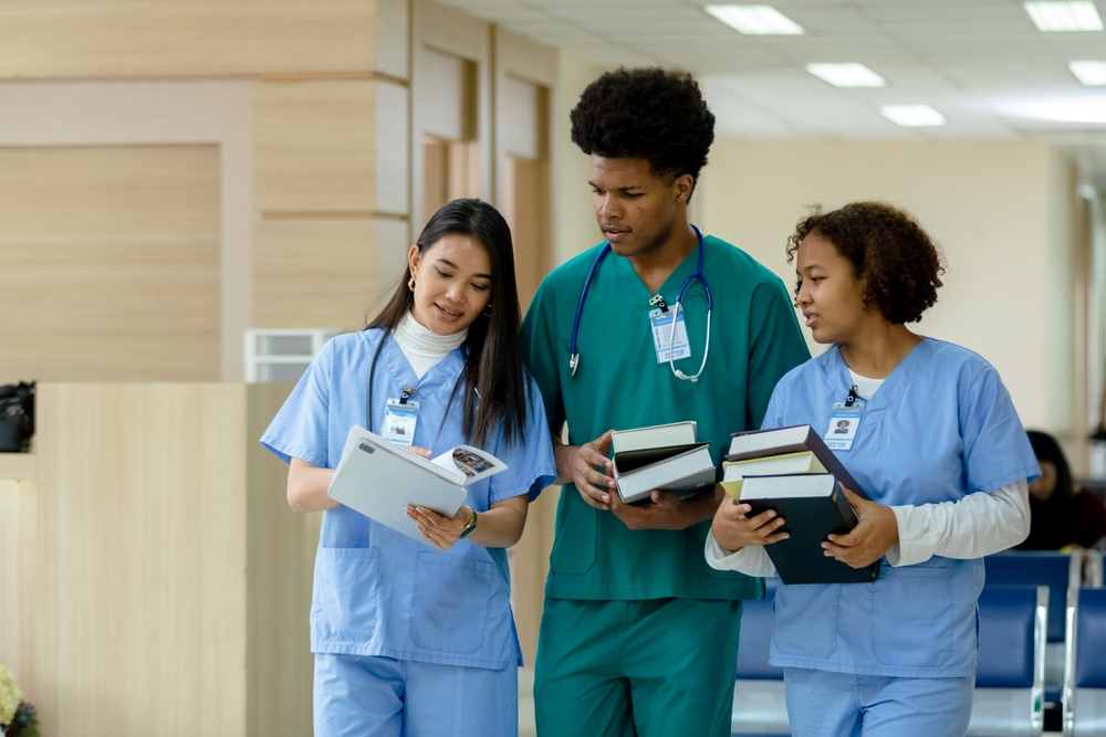 three medical staff students carrying books