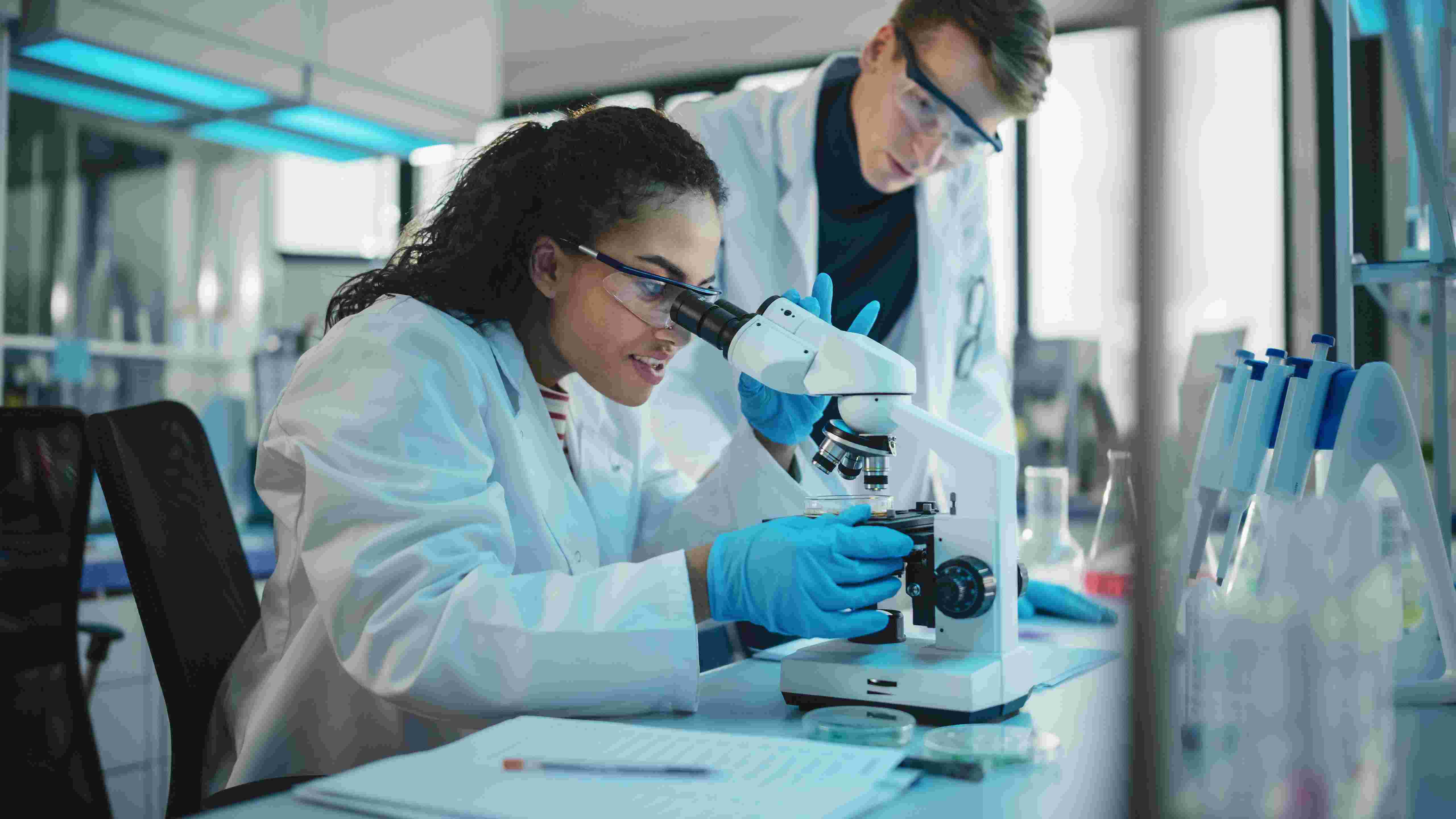two medical students in a research lab looking at microscope 